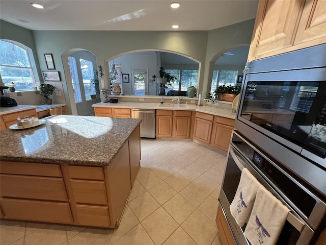 kitchen featuring light tile patterned flooring, appliances with stainless steel finishes, a center island, and sink