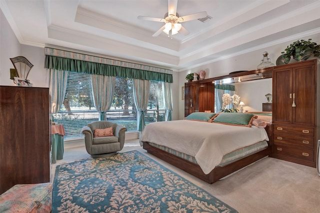 bedroom with a tray ceiling, ceiling fan, crown molding, and light colored carpet