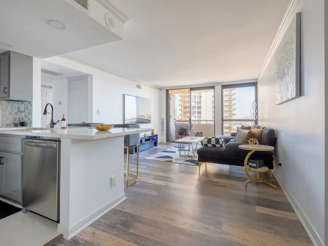 kitchen with crown molding, hardwood / wood-style floors, a kitchen breakfast bar, backsplash, and stainless steel dishwasher