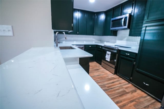 kitchen with electric stove, sink, backsplash, and hardwood / wood-style floors