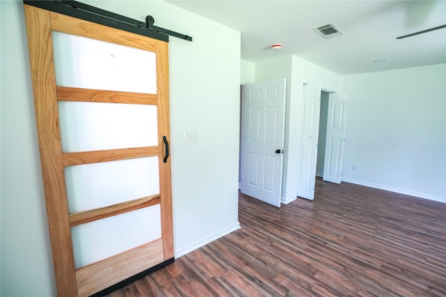 spare room with a barn door and dark hardwood / wood-style flooring