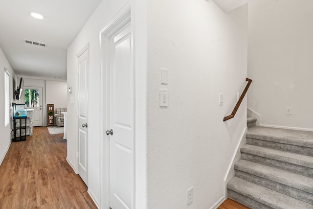 corridor featuring baseboards, stairs, visible vents, and wood finished floors