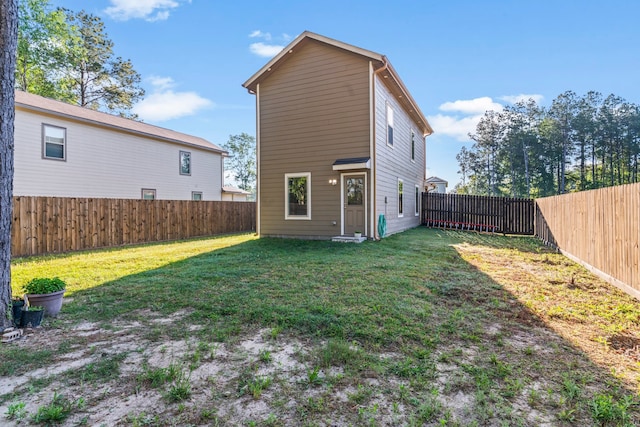 rear view of house featuring a fenced backyard and a yard