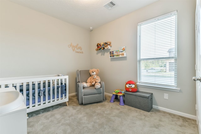 carpeted bedroom with multiple windows, a nursery area, and a textured ceiling