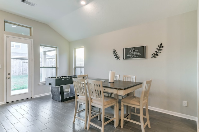 dining room with dark wood-type flooring, a wealth of natural light, and lofted ceiling