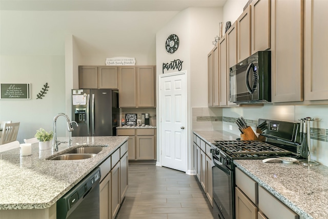 kitchen featuring light stone countertops, sink, hardwood / wood-style floors, an island with sink, and appliances with stainless steel finishes