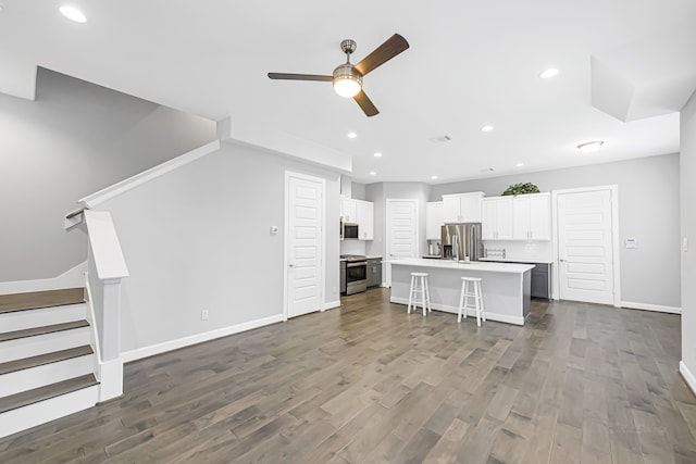 kitchen with white cabinetry, a kitchen island, stainless steel appliances, dark hardwood / wood-style floors, and a kitchen bar