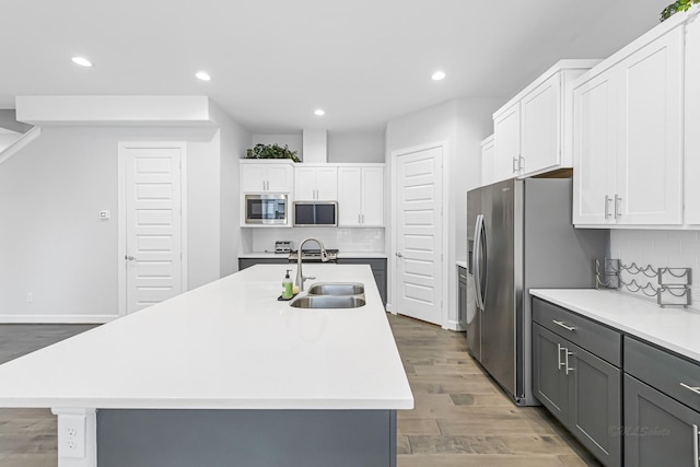 kitchen featuring stainless steel appliances, an island with sink, sink, and white cabinets