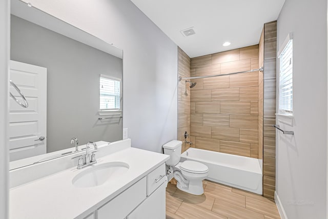 full bathroom with tiled shower / bath combo, vanity, and toilet