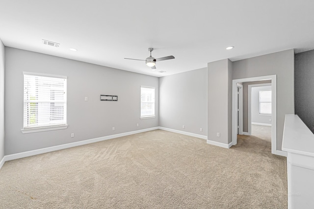 spare room with a healthy amount of sunlight, light colored carpet, and ceiling fan