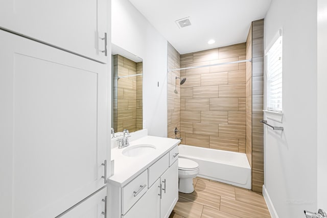 full bathroom with tiled shower / bath, vanity, and toilet