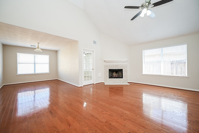 unfurnished living room featuring ceiling fan, a fireplace, hardwood / wood-style floors, and high vaulted ceiling