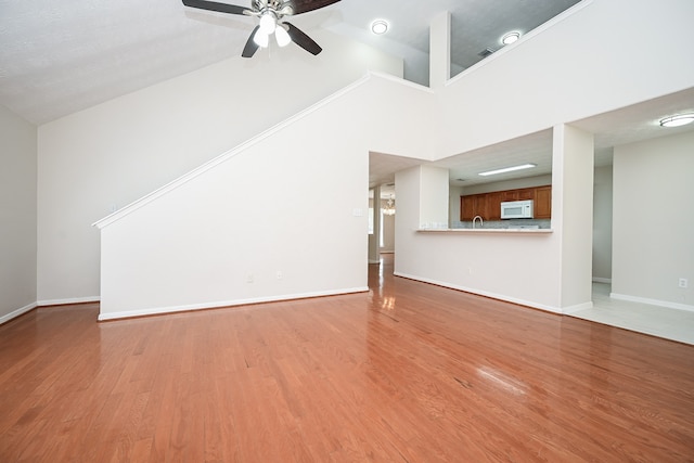 unfurnished living room with ceiling fan, ornamental molding, hardwood / wood-style floors, and high vaulted ceiling