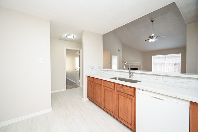 kitchen featuring ceiling fan, white dishwasher, sink, tasteful backsplash, and vaulted ceiling