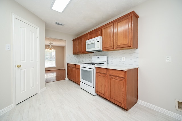 kitchen featuring decorative backsplash, white appliances, a chandelier, and a textured ceiling