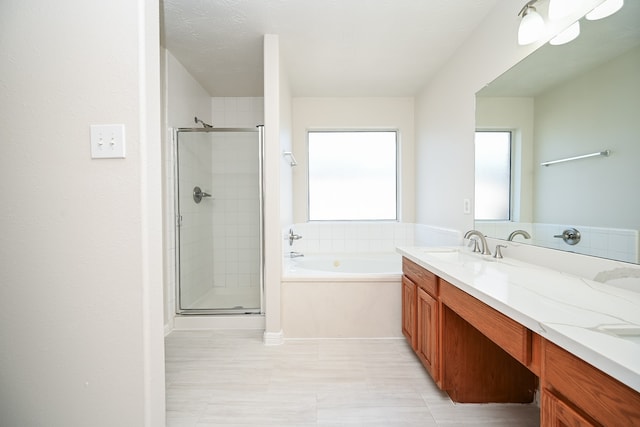 bathroom with a textured ceiling, vanity, and shower with separate bathtub