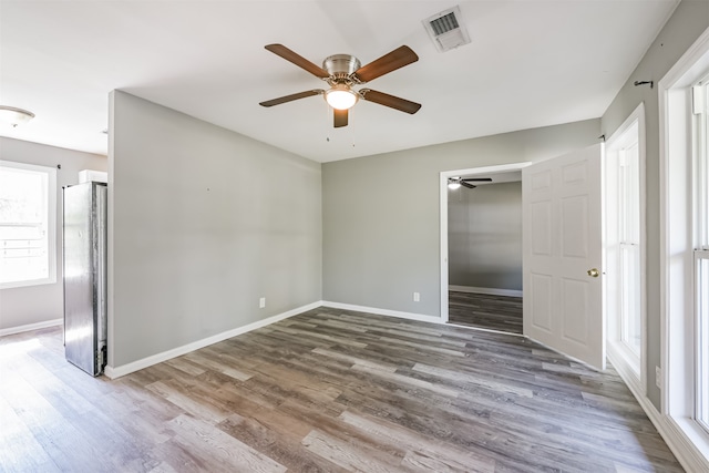 unfurnished bedroom with wood-type flooring, stainless steel fridge, and ceiling fan