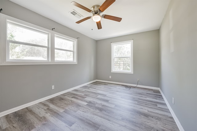 empty room with ceiling fan, light wood-type flooring, and a healthy amount of sunlight