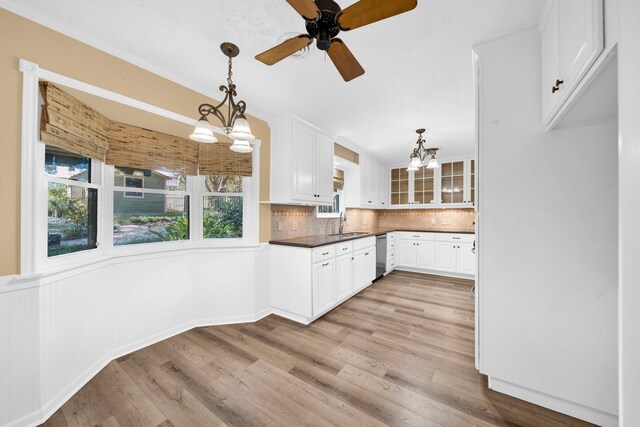 kitchen featuring stainless steel dishwasher, tasteful backsplash, sink, light hardwood / wood-style floors, and decorative light fixtures