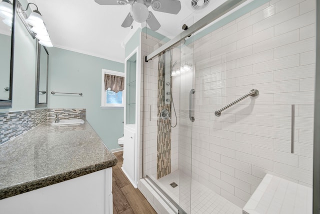 bathroom featuring vanity, backsplash, hardwood / wood-style flooring, toilet, and a shower with door