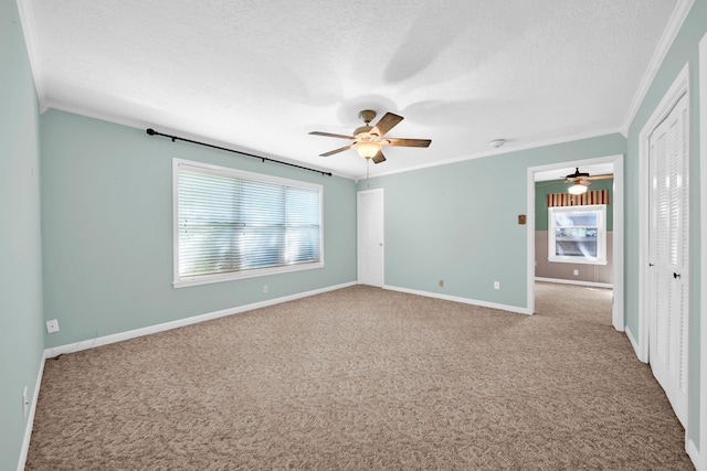 carpeted spare room featuring ornamental molding, ceiling fan, and a textured ceiling