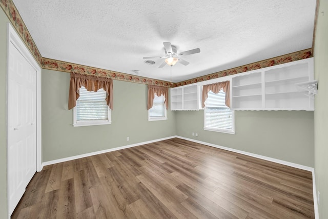 spare room featuring wood-type flooring, a textured ceiling, and plenty of natural light