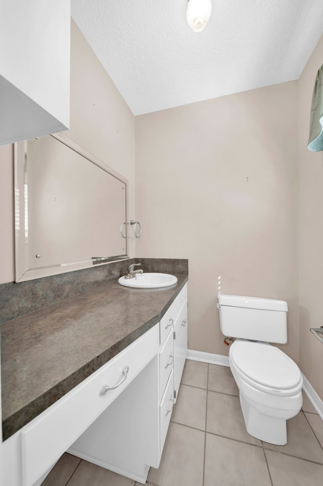 bathroom with tile patterned floors, toilet, vanity, and a textured ceiling