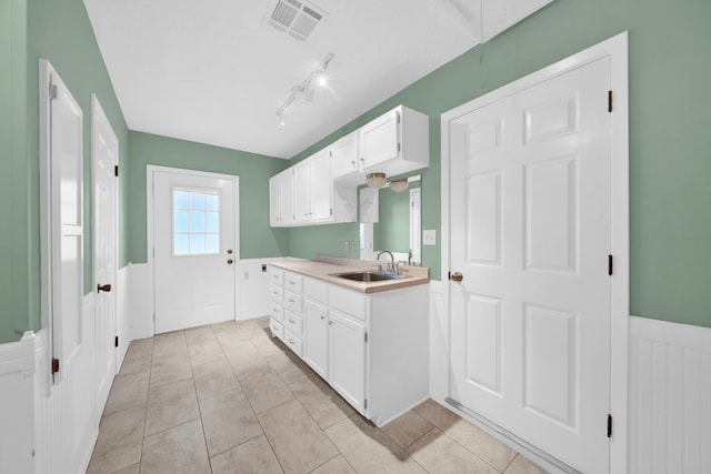 kitchen with white cabinets, light tile patterned flooring, sink, and rail lighting