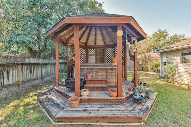 wooden deck featuring a fenced backyard, a fire pit, a gazebo, a yard, and a hot tub