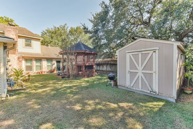 view of yard featuring a gazebo, a shed, an outdoor structure, and fence