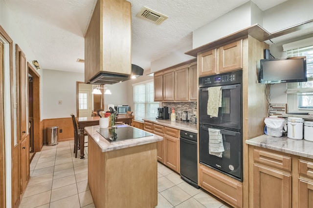 kitchen with visible vents, a kitchen island, light stone countertops, black appliances, and light tile patterned flooring