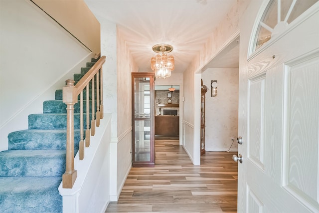 foyer with stairway, light wood finished floors, and an inviting chandelier