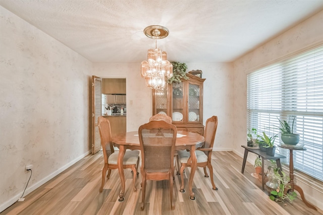 dining room featuring a chandelier, light wood-style flooring, and baseboards