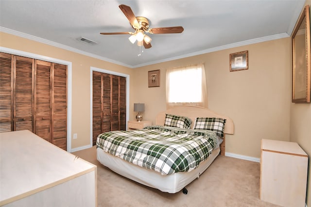 bedroom with crown molding, two closets, light colored carpet, and ceiling fan