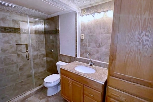 bathroom featuring vanity, toilet, and an enclosed shower