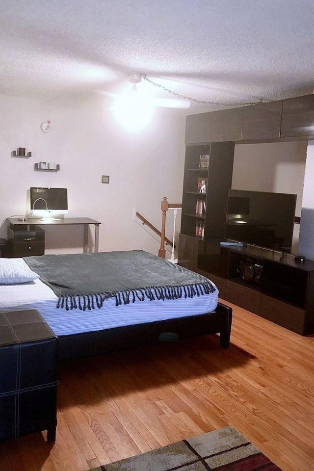 bedroom with wood-type flooring, a textured ceiling, and ceiling fan