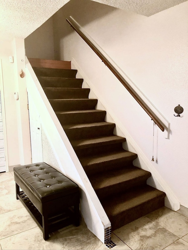 staircase with tile patterned flooring and a textured ceiling