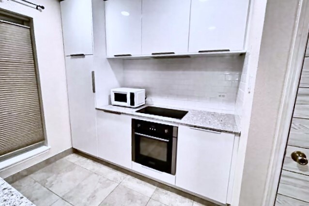 kitchen with black appliances, light stone countertops, and white cabinets