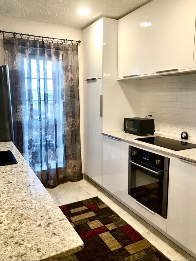 3600 Jeanetta St Unit 502, Houston, TX 77063 - kitchen with black appliances, white cabinetry, backsplash, a textured ceiling, and modern cabinets