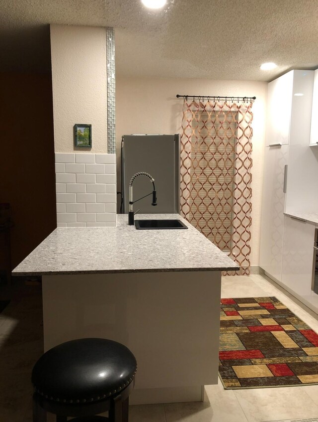 3600 Jeanetta St Unit 502, Houston, TX 77063 - kitchen featuring freestanding refrigerator, a sink, a textured ceiling, light countertops, and a kitchen bar