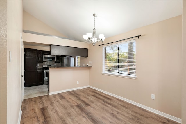 kitchen featuring light wood-type flooring, kitchen peninsula, pendant lighting, vaulted ceiling, and appliances with stainless steel finishes