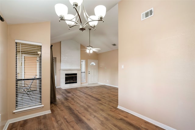 unfurnished living room with ceiling fan with notable chandelier, a large fireplace, vaulted ceiling, and dark hardwood / wood-style floors