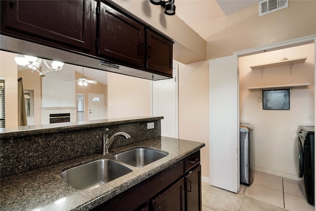 kitchen with a large fireplace, washing machine and dryer, sink, and dark stone countertops