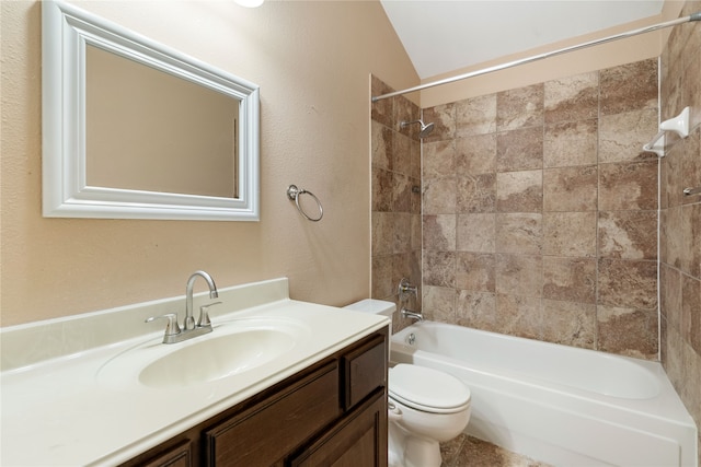 full bathroom with tiled shower / bath, vanity, vaulted ceiling, and toilet