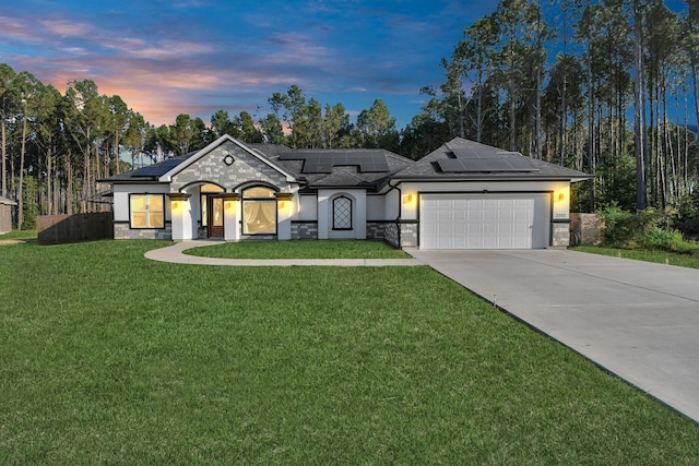 view of front of property with solar panels, a lawn, and a garage