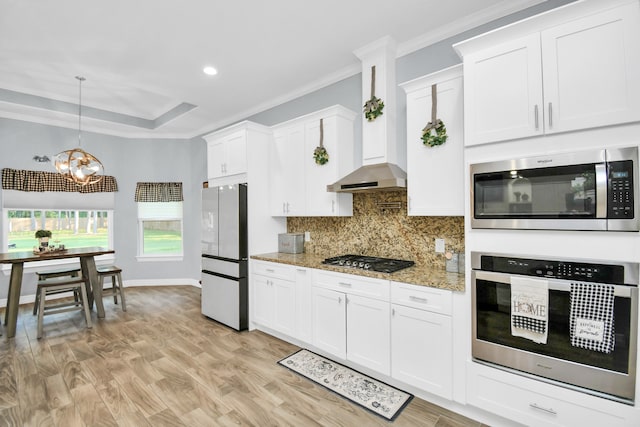 kitchen featuring light hardwood / wood-style floors, crown molding, decorative light fixtures, stainless steel appliances, and white cabinetry