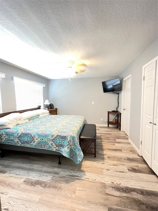 bedroom with wood-type flooring, a textured ceiling, and ceiling fan