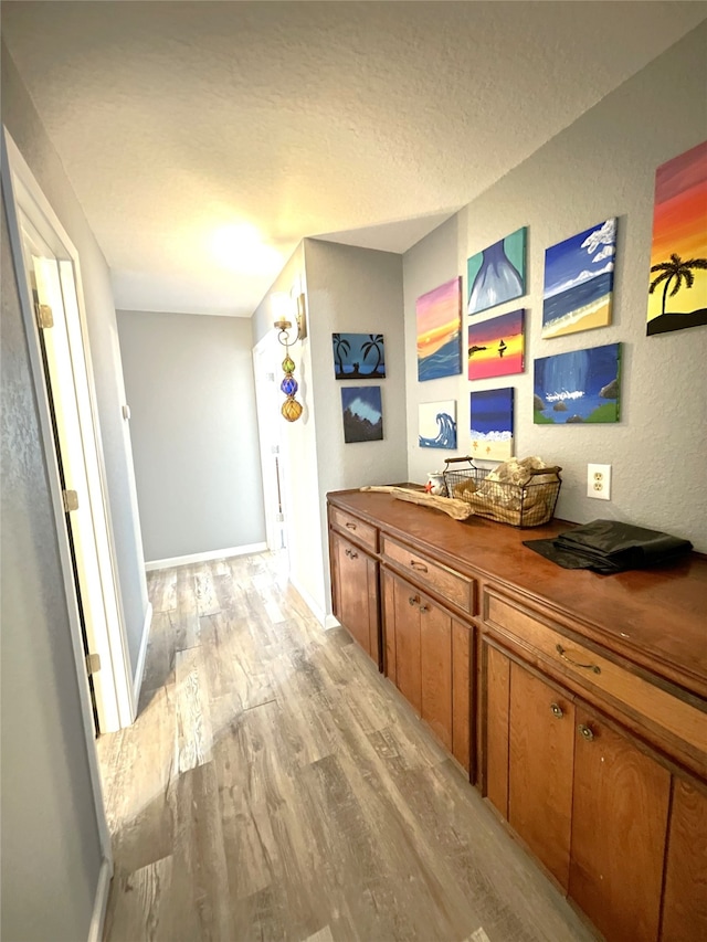 hall with light wood-type flooring and a textured ceiling