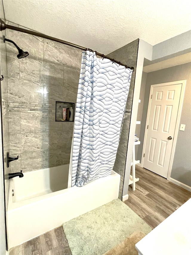 bathroom featuring hardwood / wood-style flooring, shower / bath combo with shower curtain, and a textured ceiling