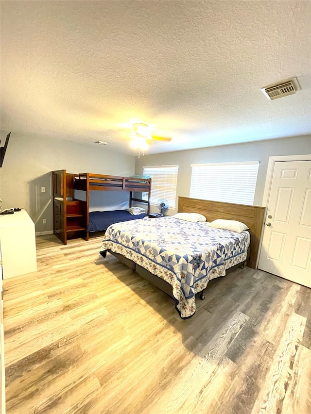 bedroom with ceiling fan, a textured ceiling, and hardwood / wood-style floors